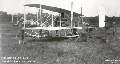 Starting up the Military Flyer engine with Wilbur Wright (fourth from left, behind engine) looking on at College Park, October 1909. Personnel are from the Army Signal Corp. Photo courtesy of the College Park Aviation Museum.