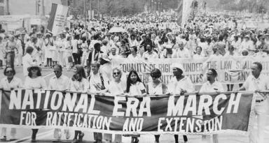 A group of demonstrators march with a large banner reading "National ERA March for Ratification and Extension" in their hands