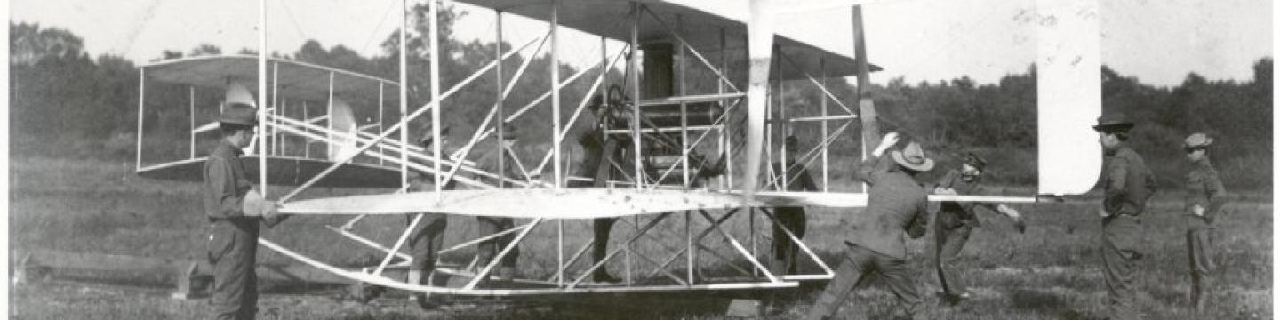Starting up the Military Flyer engine with Wilbur Wright (fourth from left, behind engine) looking on at College Park, October 1909. Personnel are from the Army Signal Corp. Photo courtesy of the College Park Aviation Museum.