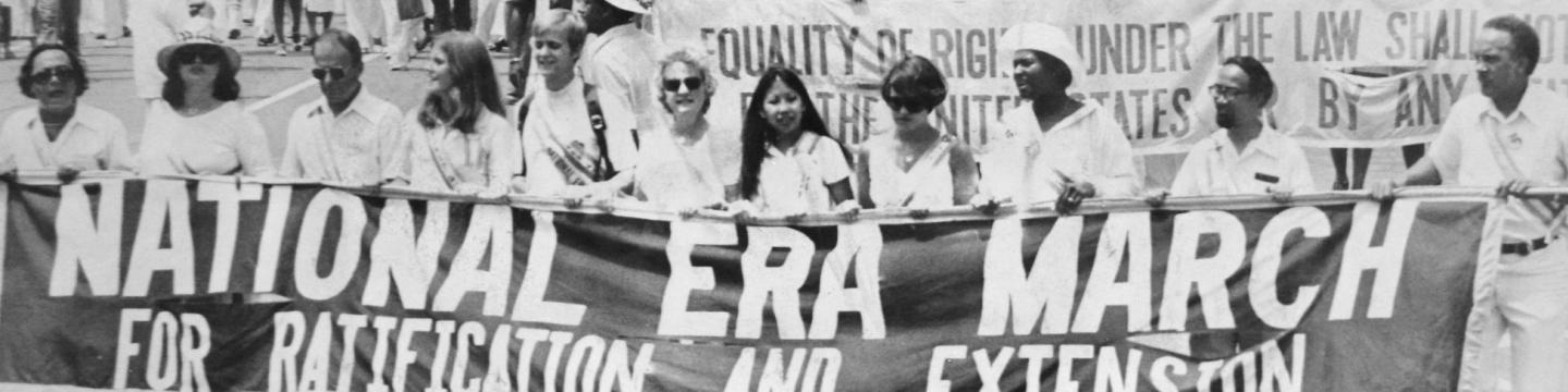 A group of demonstrators march with a large banner reading "National ERA March for Ratification and Extension" in their hands